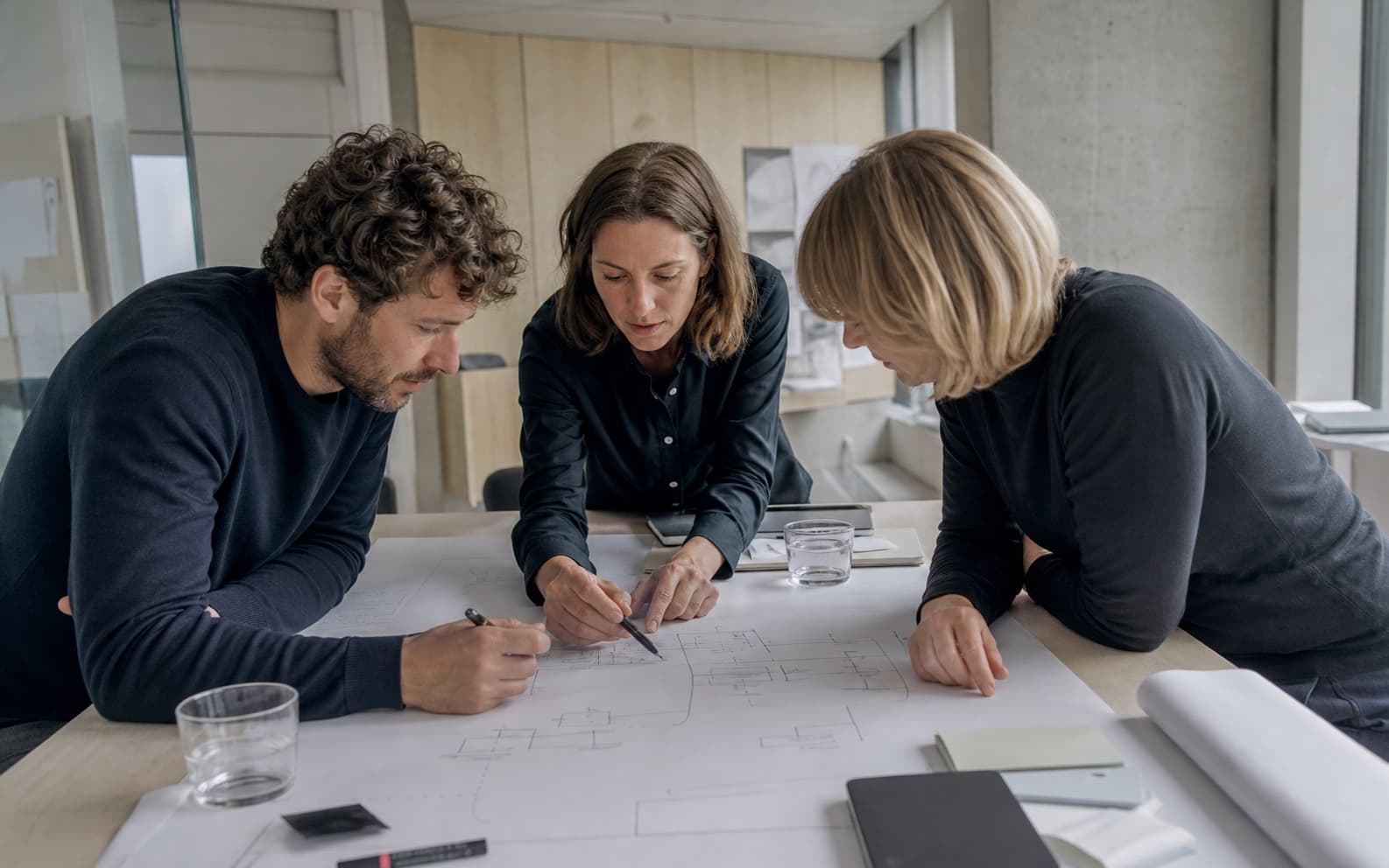 Dreiköpfiges Team analysiert gemeinsam einen Prozess auf großem Papier