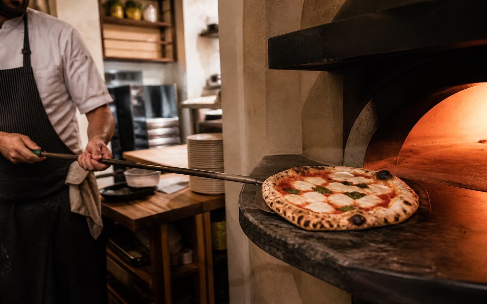 Pizza Margherita wird aus einem glühenden Steinofen gehoben